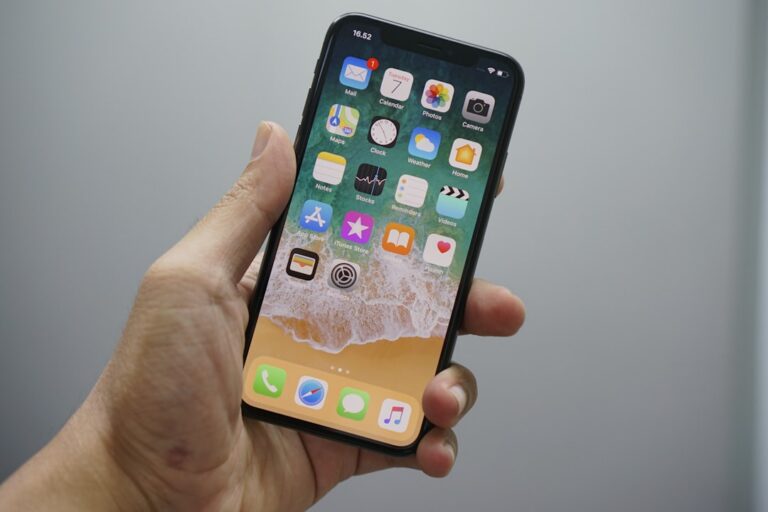 A hand holding a smartphone displaying a home screen with various app icons